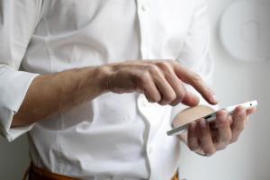 Image of person in a white shirt holding a smartphone.